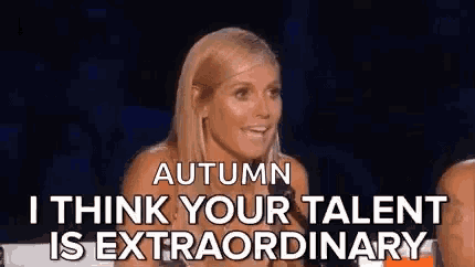 a woman is sitting in front of a crowd and talking about her talent .