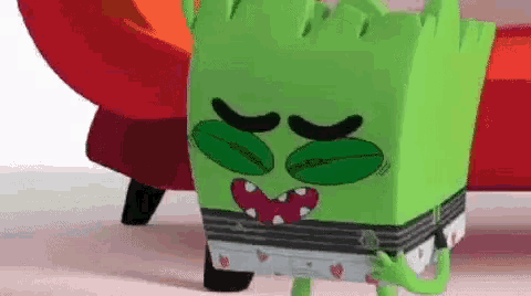 a green monster is standing next to a red couch .