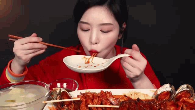 a woman is eating a plate of food with chopsticks and a spoon