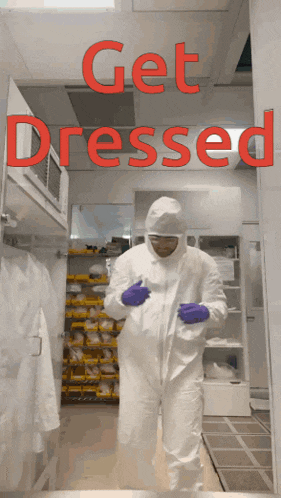 a man in a protective suit is standing in a room that says get dressed