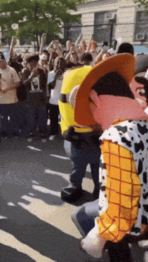 a crowd of people are gathered in front of a toy story character