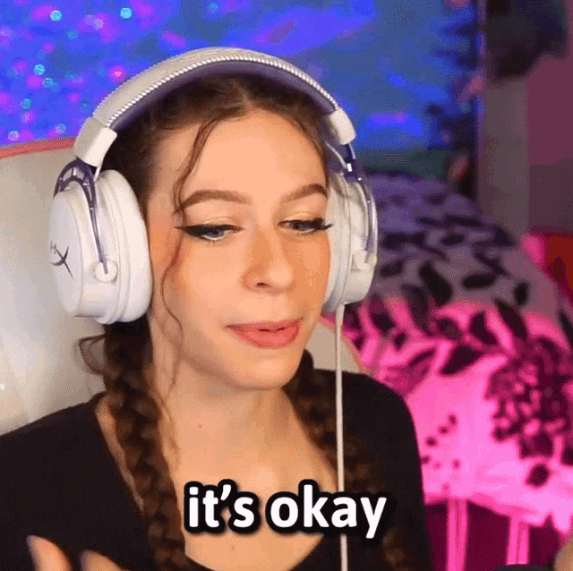 a woman wearing headphones says " it 's okay " in white letters
