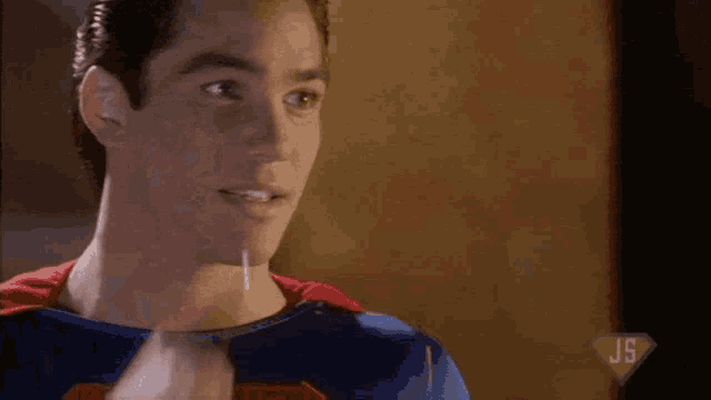 a man in a superman costume holds a pair of glasses in his hand