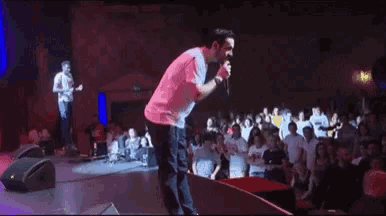 a man is singing into a microphone on stage in front of a crowd