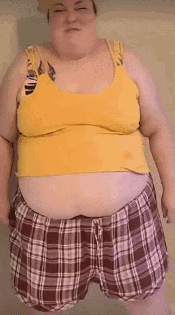 a very fat woman wearing plaid shorts and a yellow top