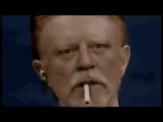 a man with red hair and a beard smoking a cigarette
