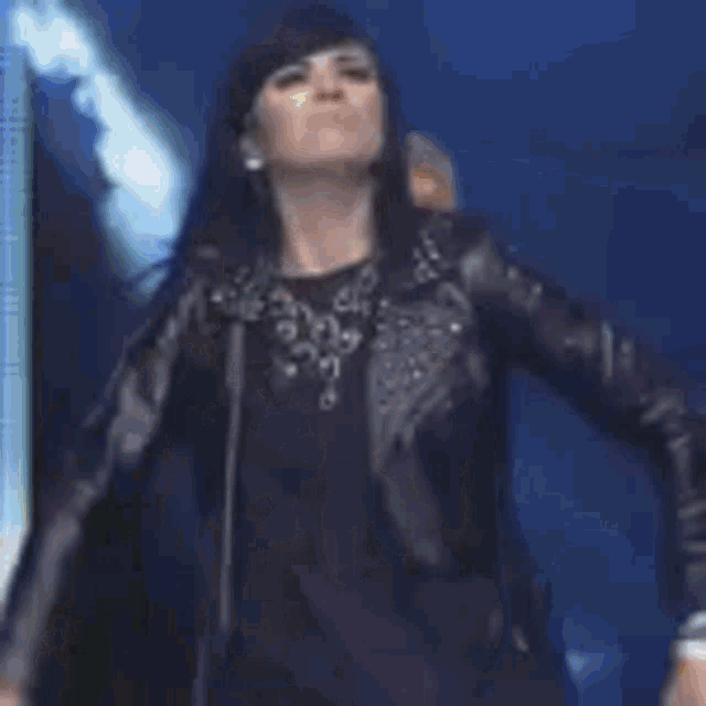 a woman is singing into a microphone on a stage and smiling .
