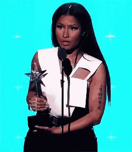 nicki minaj is holding a trophy and speaking into a microphone .