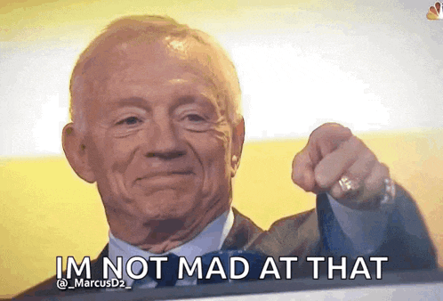 an older man in a suit and tie is pointing at the camera and says i 'm not mad at that .