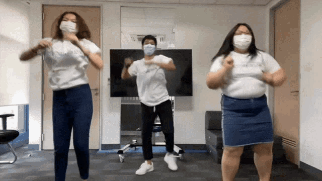 three people wearing masks are dancing in a room