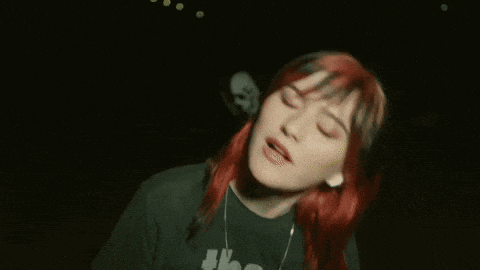 a woman with red hair is wearing a black shirt that says " the strokes "