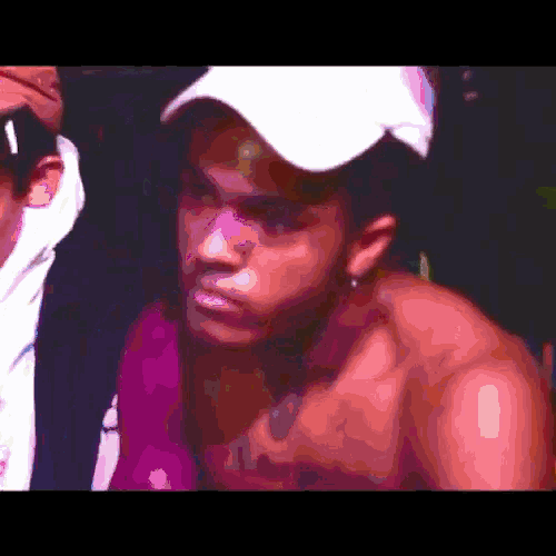 a shirtless man wearing a white hat looks at the camera .