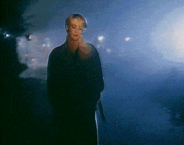 a woman in a black coat is standing in a foggy area