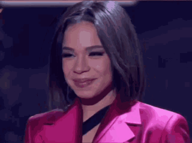a woman is wearing a pink jacket and smiling .