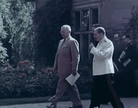 two men in suits are walking down a street