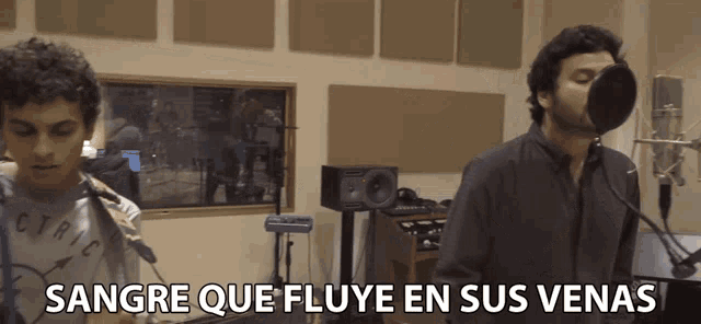 two men singing into microphones with the words sangre que fluye en sus venas below them