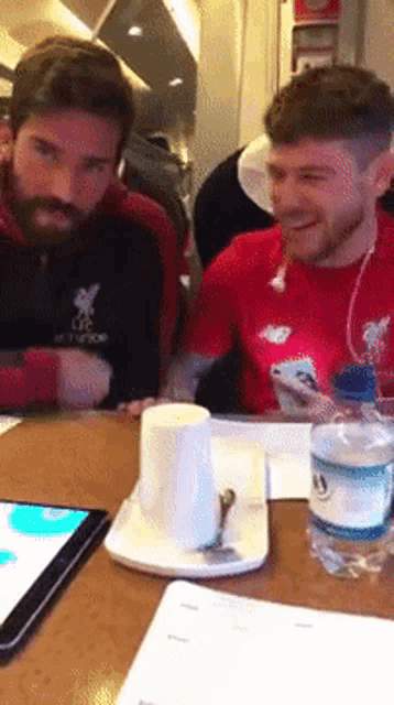 two men sit at a table with a bottle of water