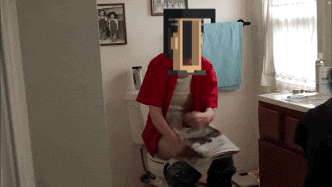 a man in a red shirt sits on a toilet
