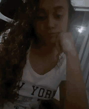 a woman with curly hair is wearing a white shirt that says new york on it .