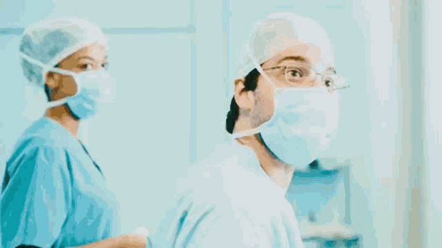 a man and a woman are wearing surgical masks in a surgery room .