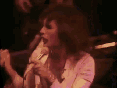 a woman is singing into a microphone on stage .