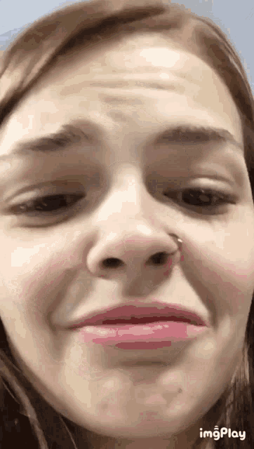 a close up of a woman 's face with a nose ring on it