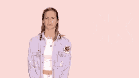 a woman in a purple shirt is making a funny face in front of a pink background with the word ok .