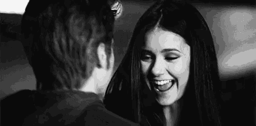 a black and white photo of a man and a woman looking at each other and smiling .