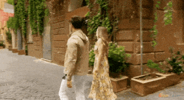 a man and a woman are walking down a cobblestone street in front of a building that says nickelodeon on it