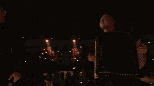 a man playing an accordion and another man singing on stage