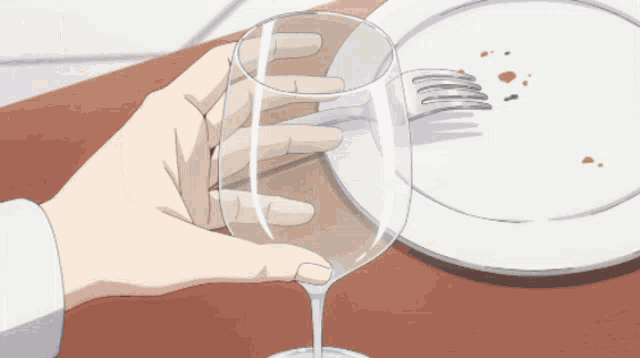 a person holding a wine glass next to a plate with a fork