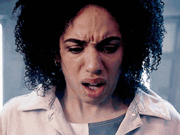 a woman with curly hair is making a funny face while wearing a white lab coat .