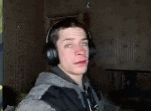 a young man wearing headphones is making a funny face in a dark room .