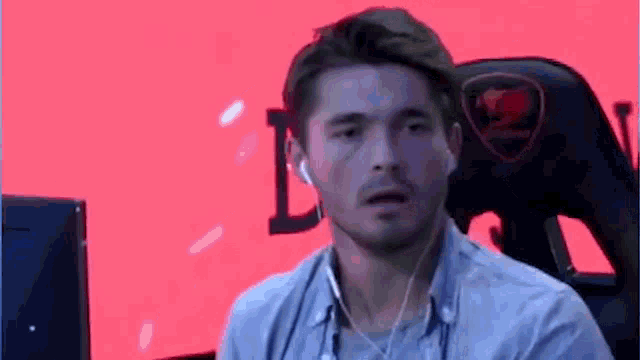 a man wearing headphones and a blue shirt is sitting in front of a computer .