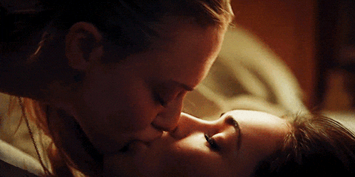 a close up of two women kissing each other on a bed .