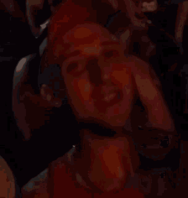 a man wearing a red hat and a red tank top is standing in a crowd of people .