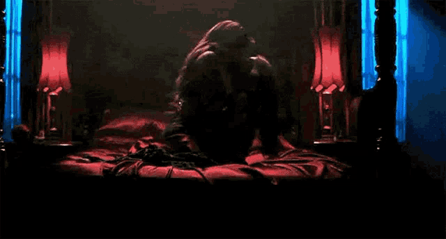 a couple is laying on a bed in a dark room with red lights .