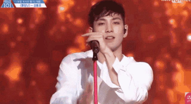 a man in a white shirt is singing into a microphone on a stage .