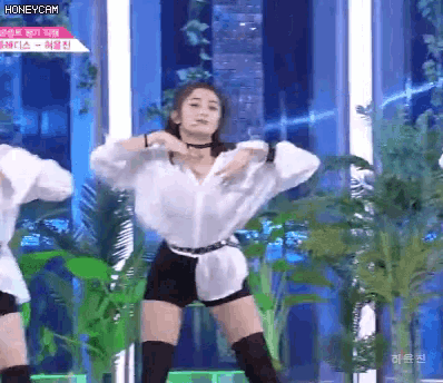 a woman in a white shirt and black shorts is dancing on a stage