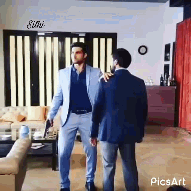 a man in a suit is standing next to another man in a suit in a living room .