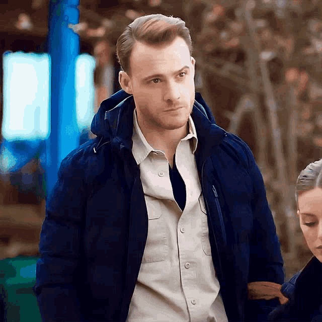 a man in a blue jacket is standing next to a woman .