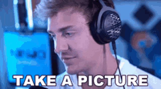a man wearing headphones is talking into a microphone and says take a picture .