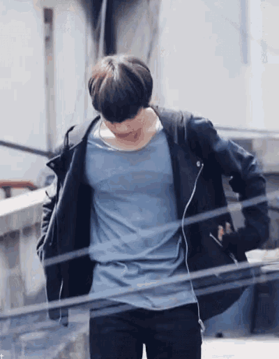 a man wearing a blue shirt and a black jacket is walking down the street