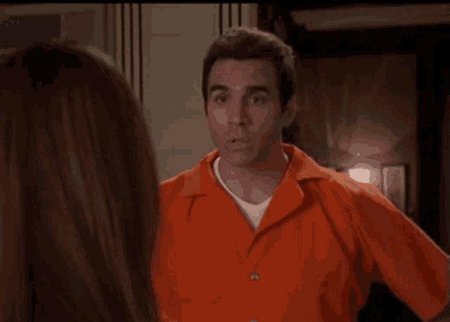 a man in an orange prison uniform is smiling at a woman