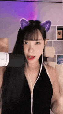 a woman wearing a cat ear headband is holding a microphone in front of her face .
