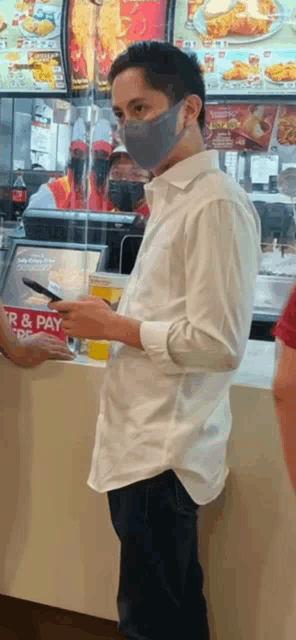 a man wearing a face mask is standing in a fast food restaurant .