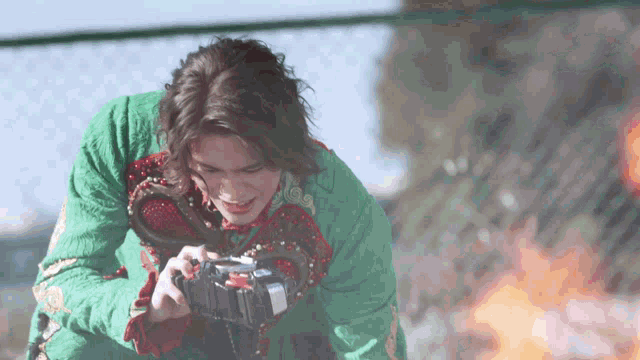 a man in a green jacket is holding a camera