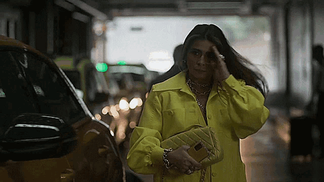 a woman in a yellow jacket holds a purse