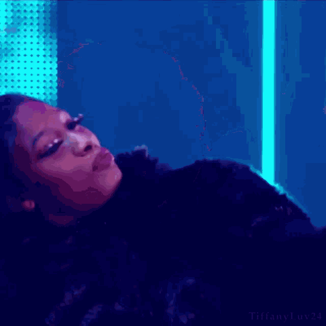 a woman with red lipstick is laying down in a dark room