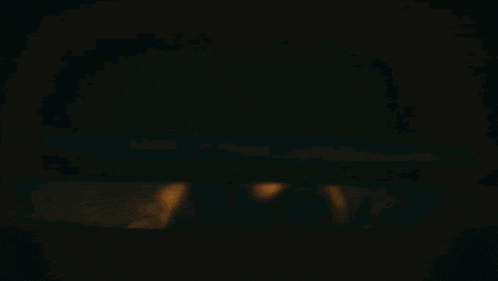 a woman in a dark room looking up at the ceiling